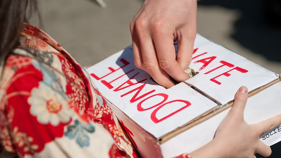 Hands placing a donation into a community donate box